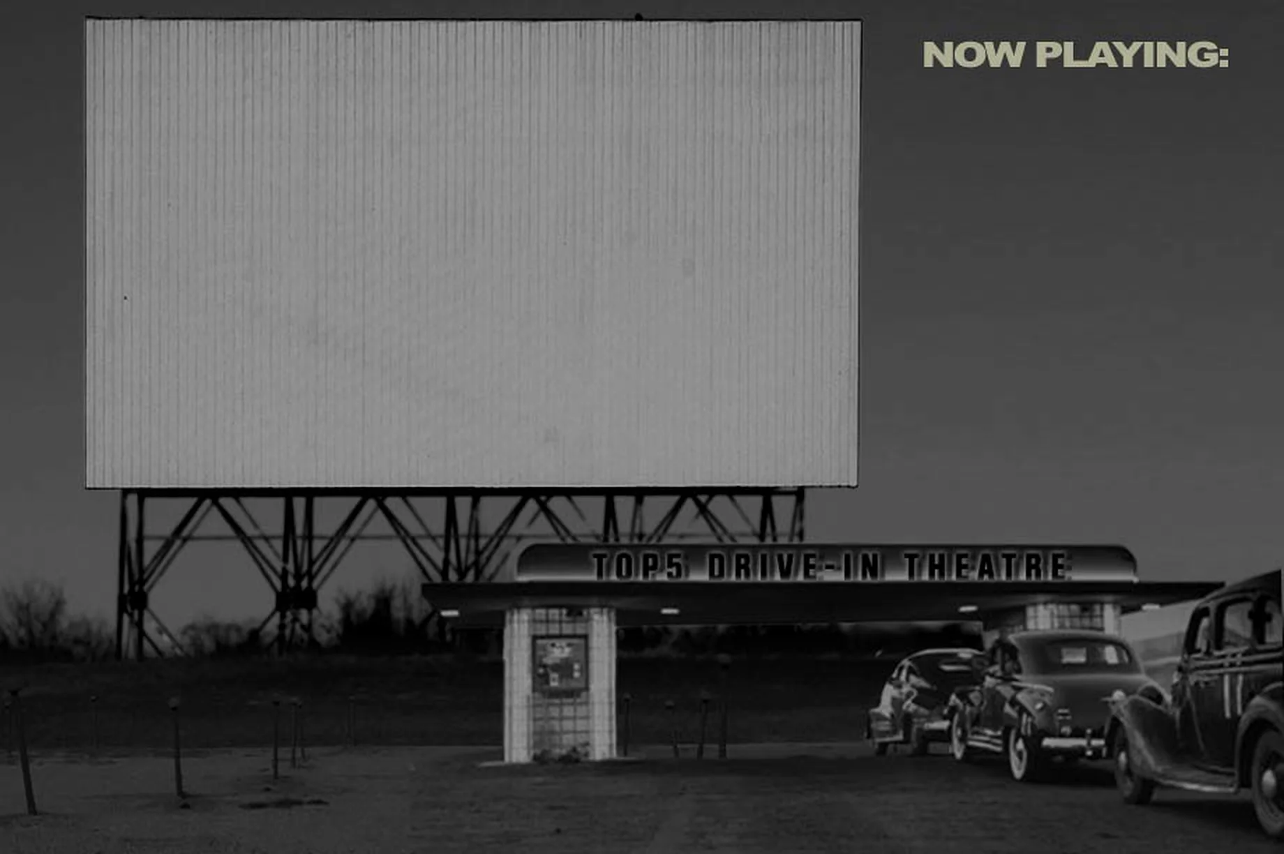 Vintage black-and-white drive-in: a painted outdoor movie screen on a pole with cars below at dusk